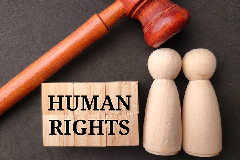 Gavel and wooden figures with word HUMAN RIGHTS on black background.