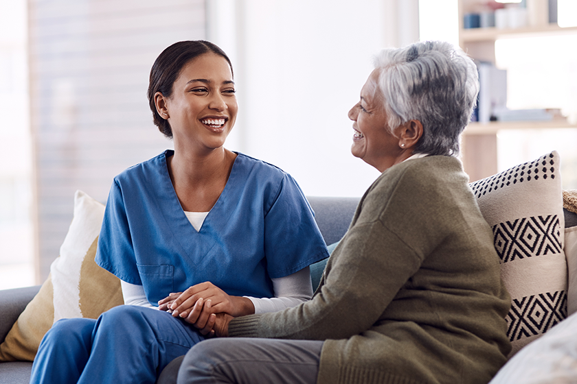 Retirement, sofa and caregiver with senior woman for conversation, chatting and support in living room. Healthcare, nursing home and female nurse with elderly patient for wellness, comfort and help. 