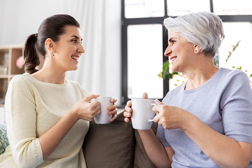 Senior mother and adult daughter drinking coffee 